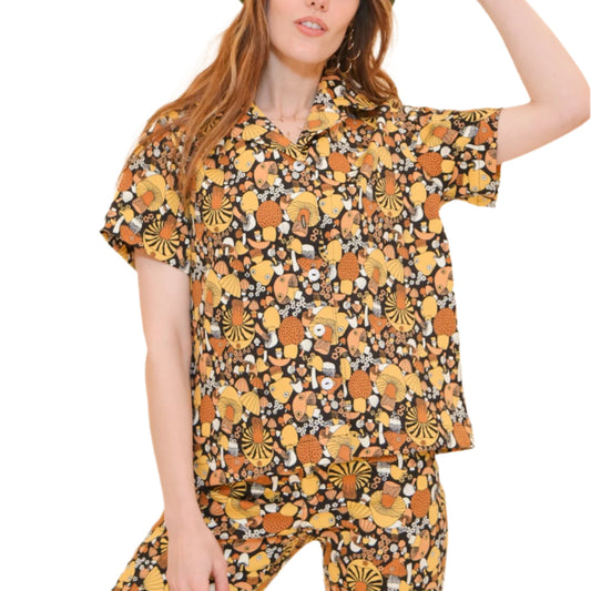 A person wearing a 'Wilson Button-Up' shirt in a mushroom print, with a beret hat, posing against a beige background.