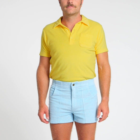 Man wearing a yellow polo shirt, light blue shorts, and a white cap on a white background
